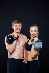 Attractive fitness people holding kettlebells isolated over gray background