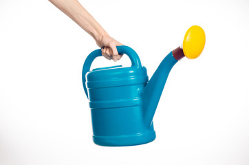 Caring for the plants and the garden theme: man's hand holding a large blue plastic watering can isolated on white background in studio