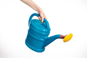 Obraz premium Caring for the plants and the garden theme: man's hand holding a large blue plastic watering can isolated on white background in studio