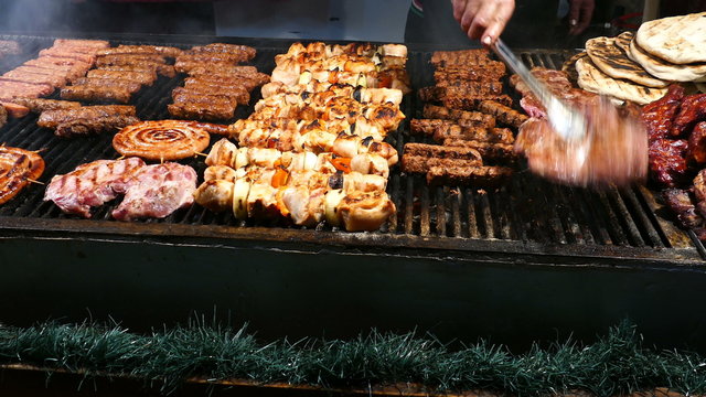 Romanian traditional sausages (mici), skewers and grill steaks on a traditional winter street fair. 4K footage.