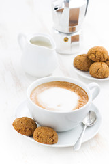 cup of cappuccino and macaroons on white table, vertical