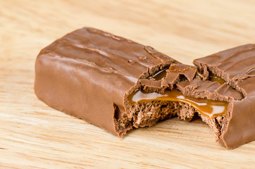 Chocolate bar with caramel toffee on wooden background.