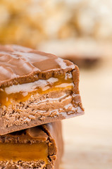 Chocolate bar with caramel toffee on wooden background.