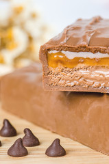 Chocolate bar with caramel toffee on wooden background.