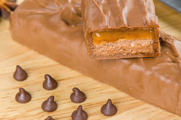 Chocolate bar with caramel toffee on wooden background.