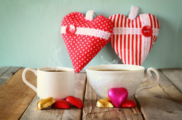 image of two red heart shape chocolates and couple cups of coffee on wooden table. valentine's day celebration concept
