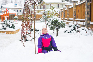 Little girl in colorful suit play in snow in back yard