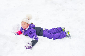 Little girl in colorful suit play in snow in back yard