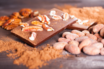 Chocolate products. Chocolate, cocoa beans, cocoa and nuts on wooden background. 
