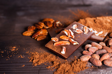 Chocolate products. Chocolate, cocoa beans, cocoa and nuts on wooden background. 