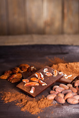 Chocolate products. Chocolate, cocoa beans, cocoa and nuts on wooden background. 