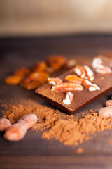 Chocolate products. Chocolate, cocoa beans, cocoa and nuts on wooden background. 