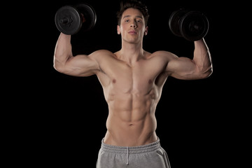 Fototapeta na wymiar muscular young man with weights on a black background
