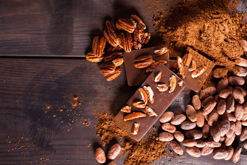 Chocolate products. Chocolate, cocoa beans, cocoa and nuts on wooden background. 