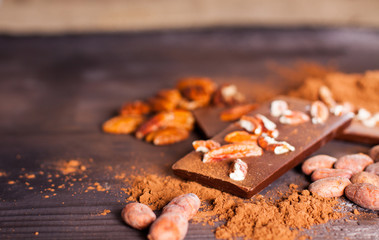 Chocolate products. Chocolate, cocoa beans, cocoa and nuts on wooden background. 