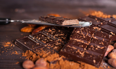 Chocolate products. Chocolate, cocoa beans, cocoa and nuts on wooden background. 