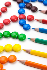 Colorful candys and penciles over white background.