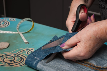 détail couturière faisant un ourlet de pantalon sur un blue jean's