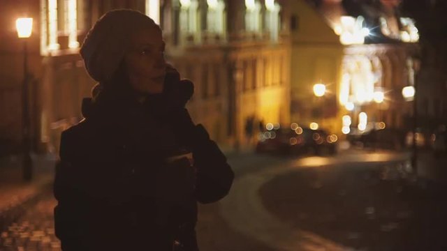 The girl on an evening street, drinking coffee