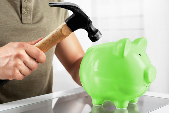 Man with a hammer going to break the piggy bank, close up