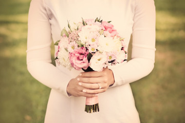 Beautiful wedding bouquet in hands of bride on nature background