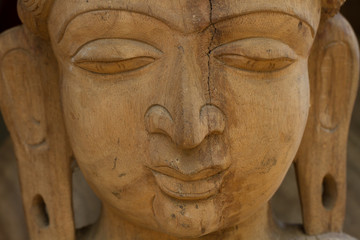 Fototapeta na wymiar Wooden face. Face of Buddha. Face carved out of wood. 