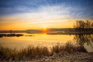 Fototapeta na wymiar Bright beautiful Sunrise over Calm Lake, River and forest horizo