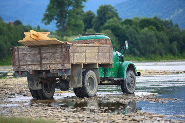 Obraz premium old truck transports cargo wade across the river