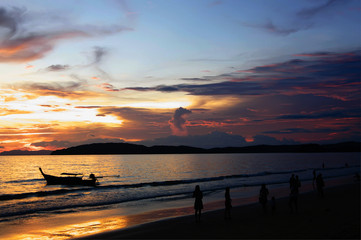 sunset on Andaman sea with silhouettes of boat, people and islands on horizon, Ao Nang beach,...
