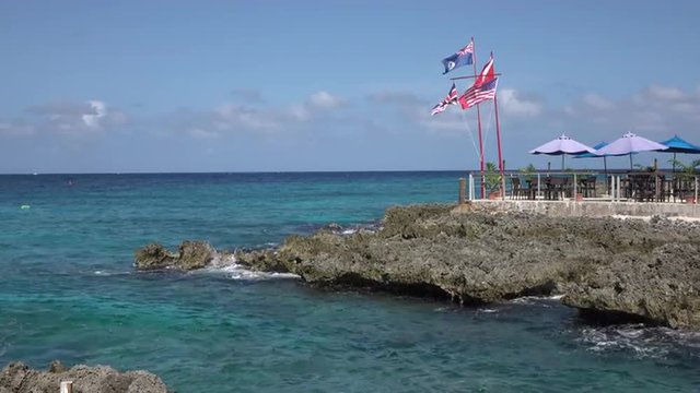Grand Cayman rocky shore national flags Caribbean. South western Caribbean is a destination for cruise ship and vacation travel especially during the colder northern winter season.