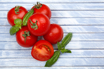 Fresh tomatoes with basil on wooden table close up