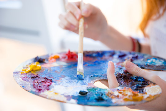 Paintbrush In Woman Hands Mixing Paints On Palette