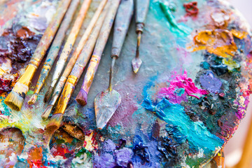 Bright mixed color paints on art palette with paintbrushes
