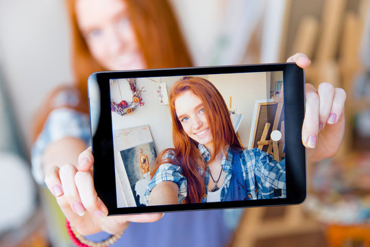 Positive smiling  woman making selfie using tablet in artist workshop
