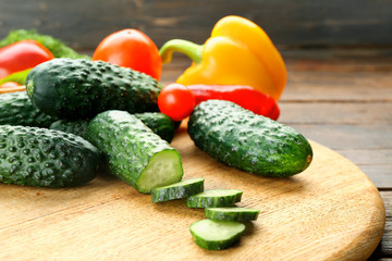 Composition of cucumbers, tomatoes and sweet peppers circles on wooden background