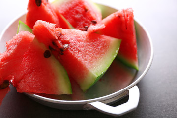 Sliced watermelon in metal bowl on grey background, close up