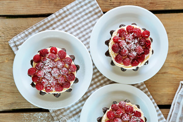 Sweet cakes with raspberries on light wooden background