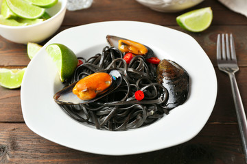 Cooked pasta, mussel and lime on brown wooden background