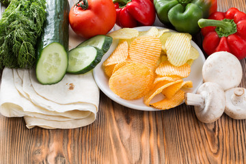 chips and vegetable on the wooden background