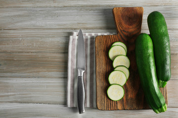 Fresh sliced zucchini on cutting board, on wooden background