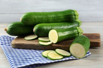 Fresh sliced zucchini on cutting board, on wooden background