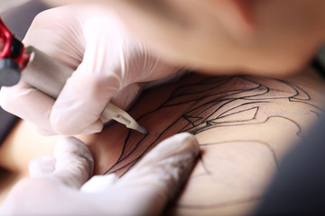 Obraz na płótnie Canvas Hands in medicine gloves make tattoo, close up