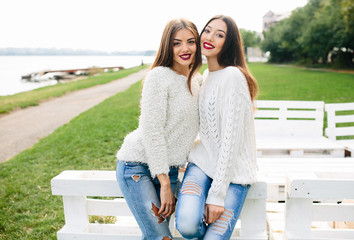 Two girls lean bench