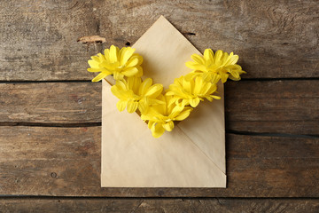 Yellow chrysanthemum in envelope on wooden background