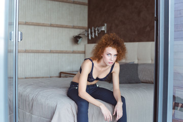 Alluring attractive young woman sitting on bed in bedroom