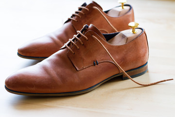 Brown leather shoes with wood shoe forms on wooden table