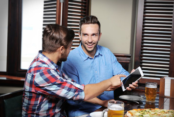 Young men drinking beer and talking in cafe