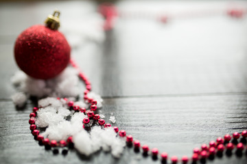 Red Christmas ball on snow on black wooden background