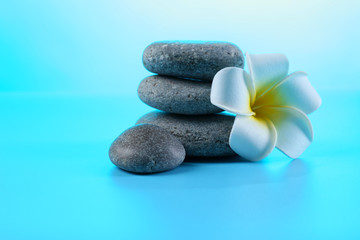 Fototapeta na wymiar Spa stones and flower on blue background