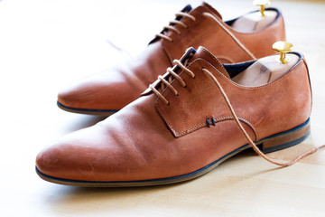 Brown leather shoes with wood shoe forms on wooden table